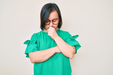 Brunette woman with down syndrome wearing casual clothes and glasses feeling unwell and coughing as symptom for cold or bronchitis. health care concept.