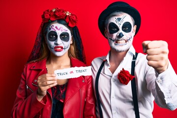 Couple wearing day of the dead costume holding trick or treat paper annoyed and frustrated shouting with anger, yelling crazy with anger and hand raised