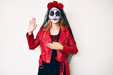 Woman wearing day of the dead costume over white swearing with hand on chest and open palm, making a loyalty promise oath