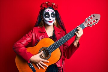 Woman wearing day of the dead costume playing classical guitar smiling looking to the side and staring away thinking.