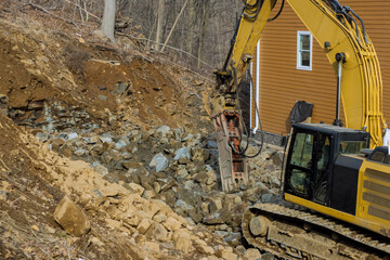 Tracked excavator with the jackhammer in a working on smashing rock