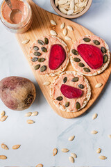 Crispy puffed rice cakes on table hummus spread and tomato and beet vegetables and sesame pumpkin seeds on the table - top view on healthy vegetarian or vegan breakfast gluten free copy space