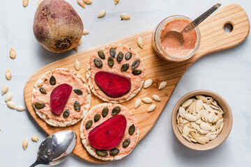 Crispy puffed rice cakes on table hummus spread and tomato and beet vegetables and sesame pumpkin seeds on the table - top view on healthy vegetarian or vegan breakfast gluten free