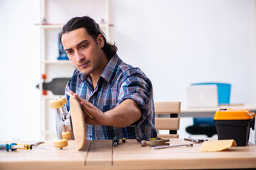 Young man repairing skateboard at workshop