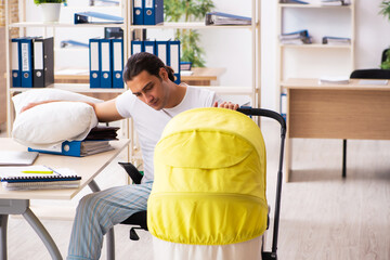Young male employee looking after newborn at workplace