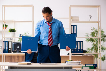 Young male employee doing sport exercises at workplace