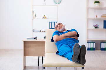 Fototapeta na wymiar Old male doctor extremely tired after night shift