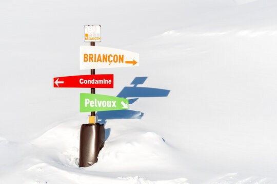 Pointer Sign At Mountains With Snow In Winter, Brianson, Alps, France. Crossroad Sign In The Alps Pointing To Cities. Colorful Directional Board Post At Ski Resort On Sunny Winter Day