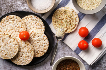 Crispy puffed rice cakes on table hummus spread and tomato vegetables and sesame seeds on the table - top view on healthy vegetarian or vegan breakfast gluten free copy space