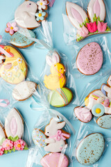 Easter cookies in personal package bag with pastel colored icing on blue background. Happy spring holiday, set of sweet gifts for anniversary, cute gingerbread