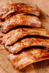 fried with spices pork ribs in a glass baking sheet on a wooden cutting board. cooked meat at home. Barbecue.