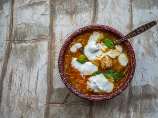 Rustic soup with vegetables and meatballs in a deep plate with a spoon