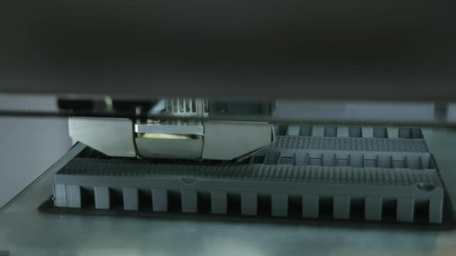 3D printer working. 3D printer, printing with plastic wire filament in additive manufacturing technique. Print head of 3D printer machine printing plastic workpiece at modern technology. 4K.