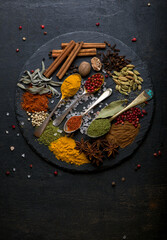 Powder spices on spoons in black wooden table background