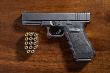 Black semi-automatic pistol and ammunition on wooden table