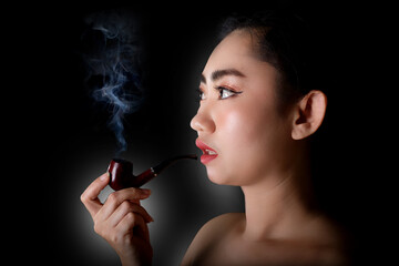 Fototapeta premium Portrait Asia young women with a smoking pipe tobacco on the black background