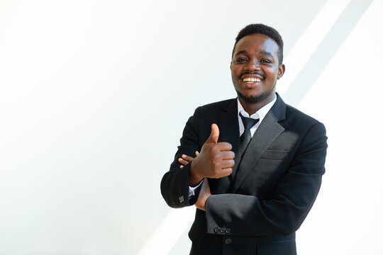 Black businessman wearing a suit shows his thumb up on white background.