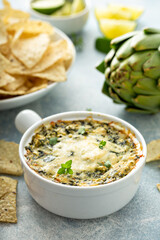 Artichoke spinach dip in a baking dish served with chips - obrazy, fototapety, plakaty