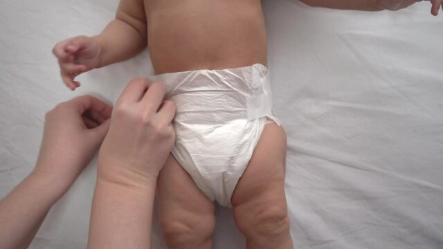 Mother puts a diaper on a newborn baby