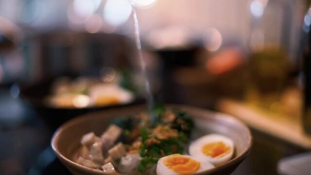 Pouring soup on the bowl of Vietnamese Noodles