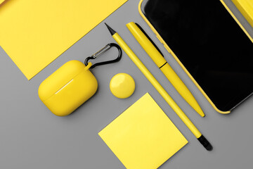 Yellow notepad with smartphone and pen on gray background