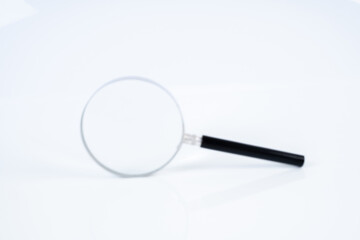 Magnifier glass and white background with blurred focus.