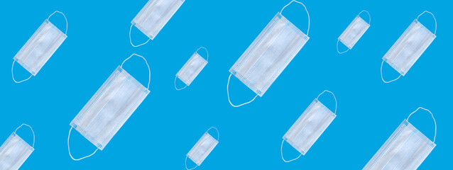Many medical masks on a blue background cover the mouth and nose to protect against viruses and bacteria. Epidemic concept. Regular pattern, flat lay.