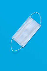 Fototapeta na wymiar Medical protective mask on a blue background. The disposable surgical face mask covers the mouth and nose. Health care and medical concept