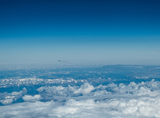 Fototapeta na wymiar White heavy clouds in the blue sky. Panoramic cloudscape above the clouds.