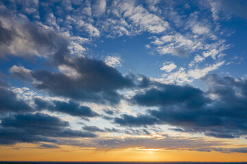 Fototapeta premium Yellow sunset and puffy clouds in the sky pierced with sun rays. Beautiful nature background.