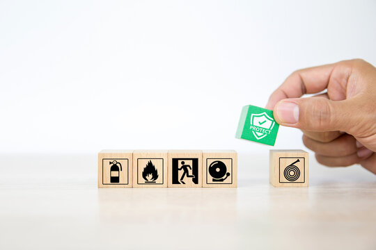 Close-up Hand Choose Wooden Toy Blocks Stacked With Fire Protect Icon With Fire Extinguisher And Door Exit Sing Symbol For Safety Prevent And Protection Is Accident Concepts.