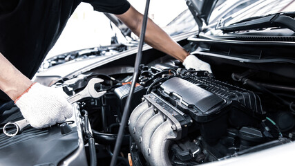 Close-up hands of auto mechanic are using the wrench to repair and maintenance auto engine is...