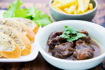 Beef stew serve with French fries and garlic bread
