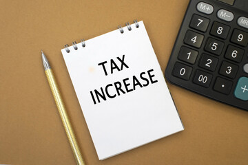 the tax increase is written in a notebook that lies among a calculator and a yellow pen. Business and financial concept