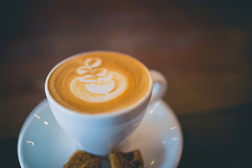 Latte hot coffee with foam milk art on a wooden table