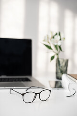 Workplace, office home desk with open laptop computer, smartphone, glasses and notebook lying on...