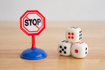 White three casino dice gambling and warning stop sign on wooden background with copy space. Gambling, betting online casino warning, social problem concept.