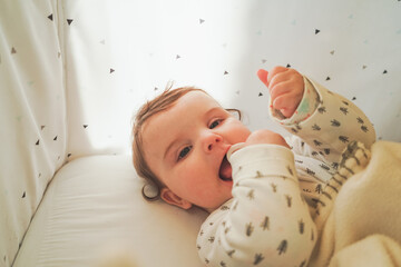 Portrait of a little playful baby in her cradle