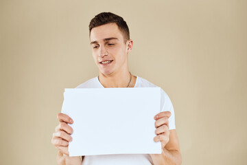 man in white t-shirt sheet of paper in hands Copy Space cropped view beige background
