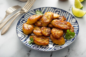 Fried caramelized plantains served with lime wedges and cilantro © fahrwasser