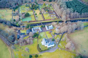 Mansion and private tennis court in real estate grounds aerial view from above