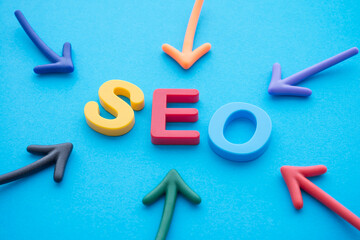 Search Engine Optimization (SEO) ranking digital marketing strategy concept. Color highlight arrows around SEO alphabets word on blue background.