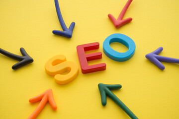 Search Engine Optimization (SEO) ranking digital marketing strategy concept. Color highlight arrows around SEO alphabets word on yellow background.