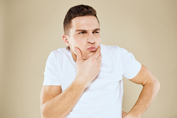 Emotional man facial expression gesture with hands white t-shirt beige background