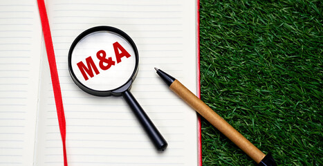 Word M and A - mergers and acquisition written on notebook red letters