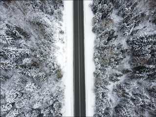 Aerial drone view of road in idyllic winter landscape. Street running through the nature from a birds eye view.