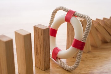 Lifebuoy stop wood block fall domino effect on office wooden table background. Life, health and...