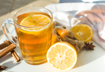 Hot Ginger tea in glass mug with lemon, honey and spices at white. Healing tea. Top view with copy space.
