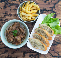 Pork stew serve with French fries and garlic bread