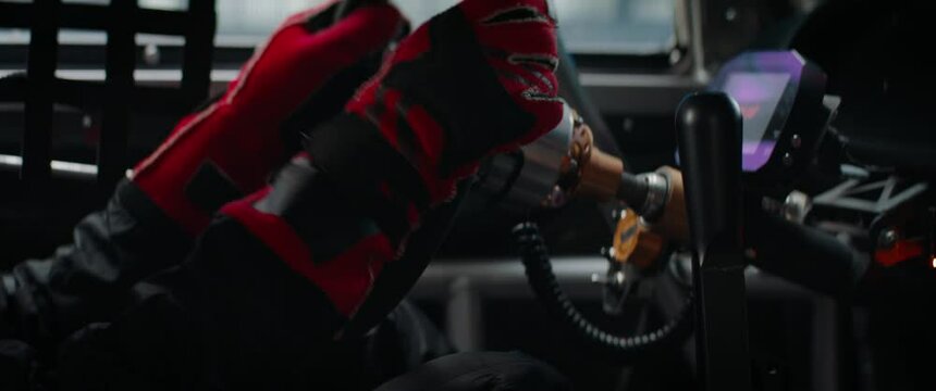 CU View of sports car driver in pushing a button to start his car on a speedway. Preparing for a race, motorsport. Daytime shot. Shot with 2x anamorphic lens